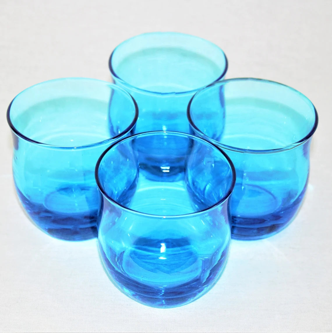 Four blue glass tumblers on a white background