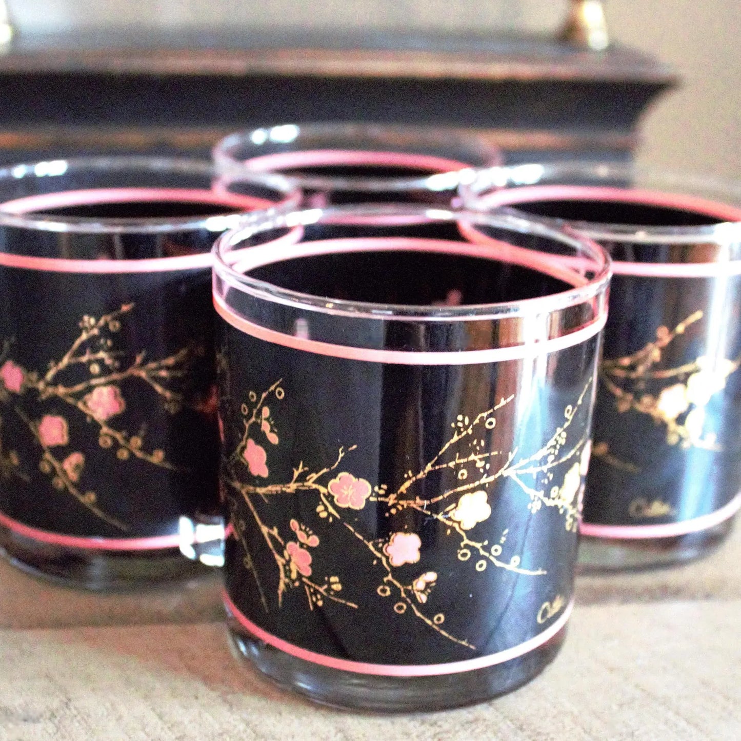 Set of black glasses with floral designs on a reflective surface