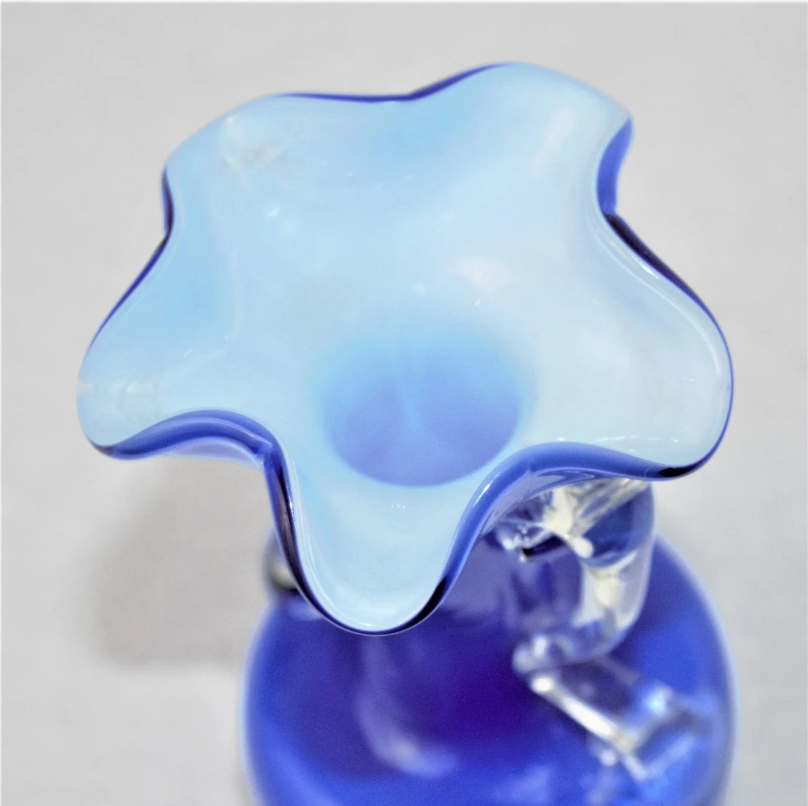 Blue and clear glass vase with a unique design on a light gray background