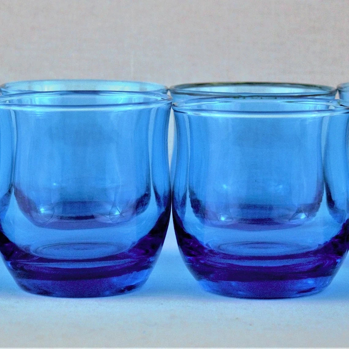 Two blue glass tumblers on a white surface