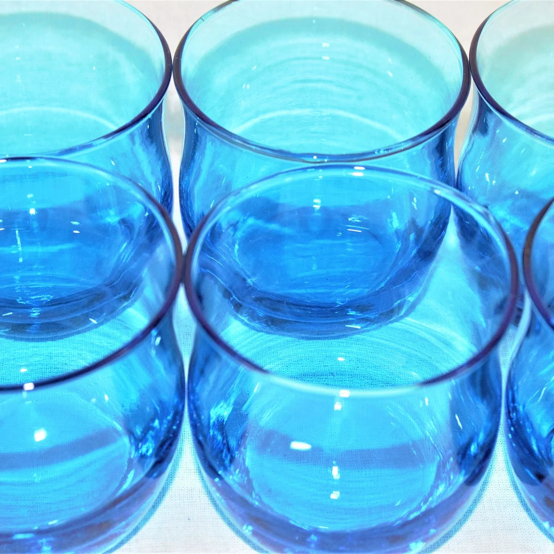 Set of six blue glass tumblers on a white background