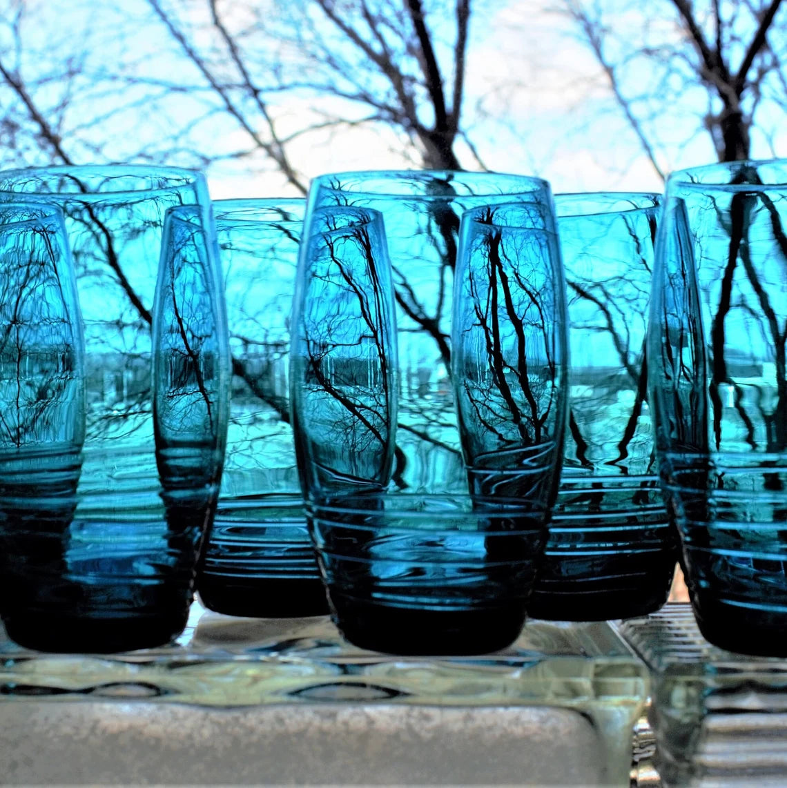 Set of blue glass tumblers with a blurred outdoor background