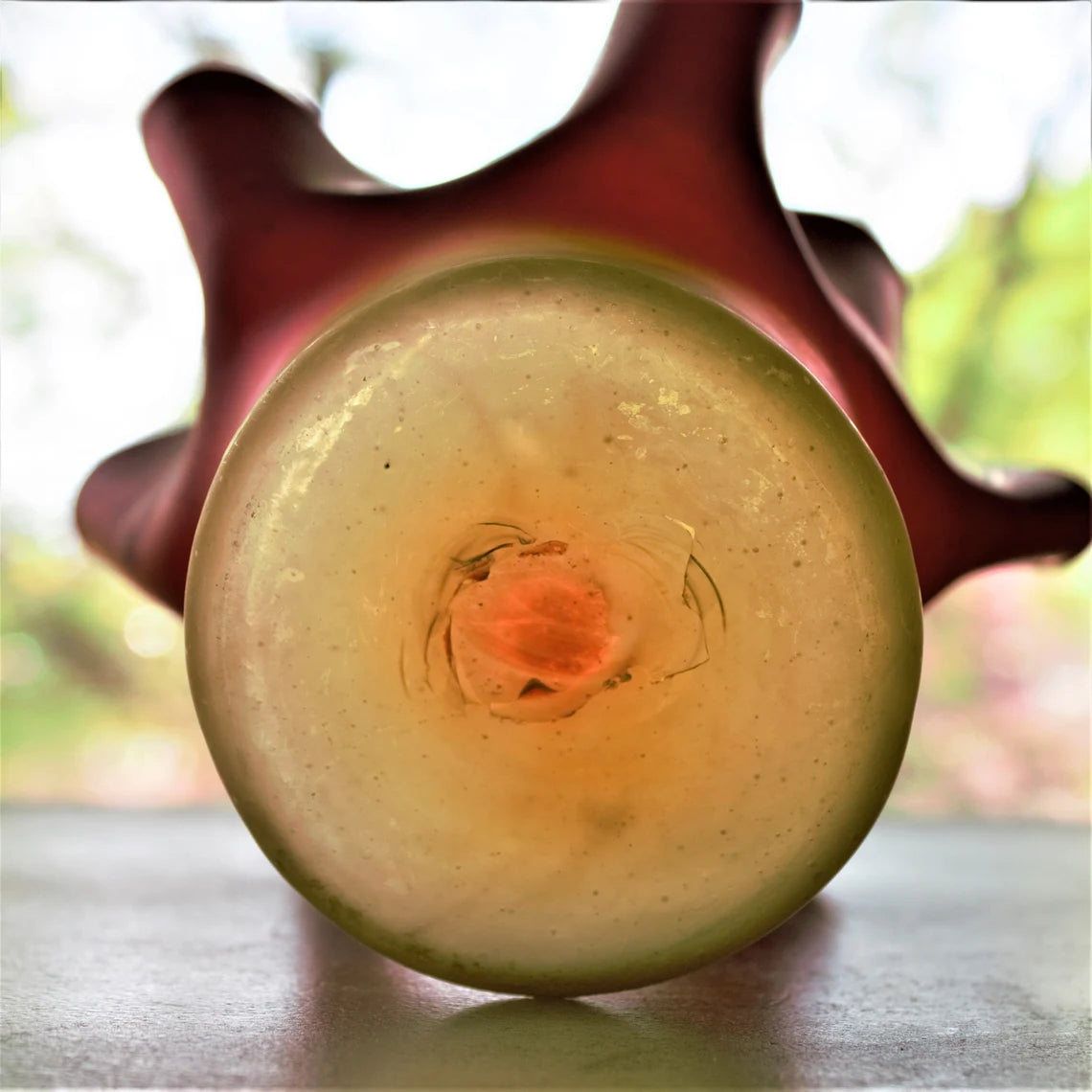 Close-up of the bottom of a glass vase with a blurred natural background