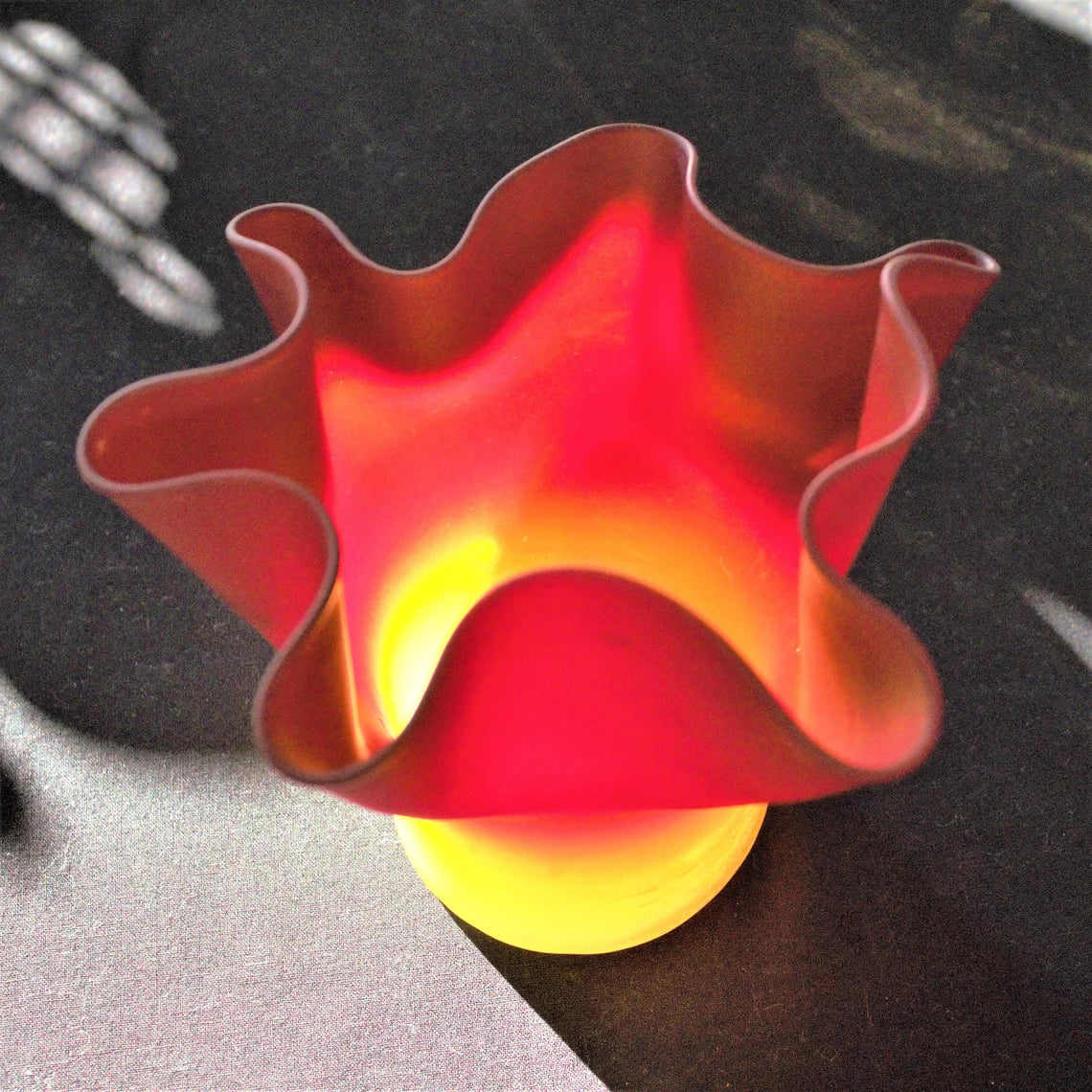Decorative red and yellow glass bowl on a dark surface