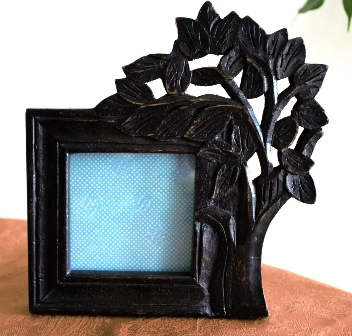 Decorative black photo frame with floral design on a wooden surface
