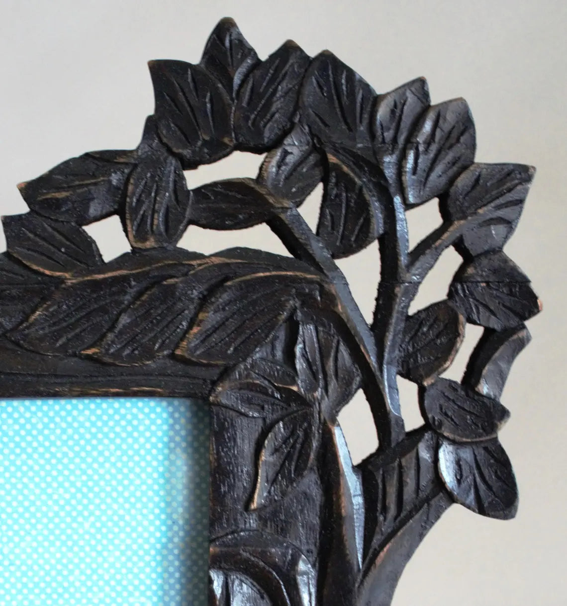 Decorative black metal frame with leaf design on a light background