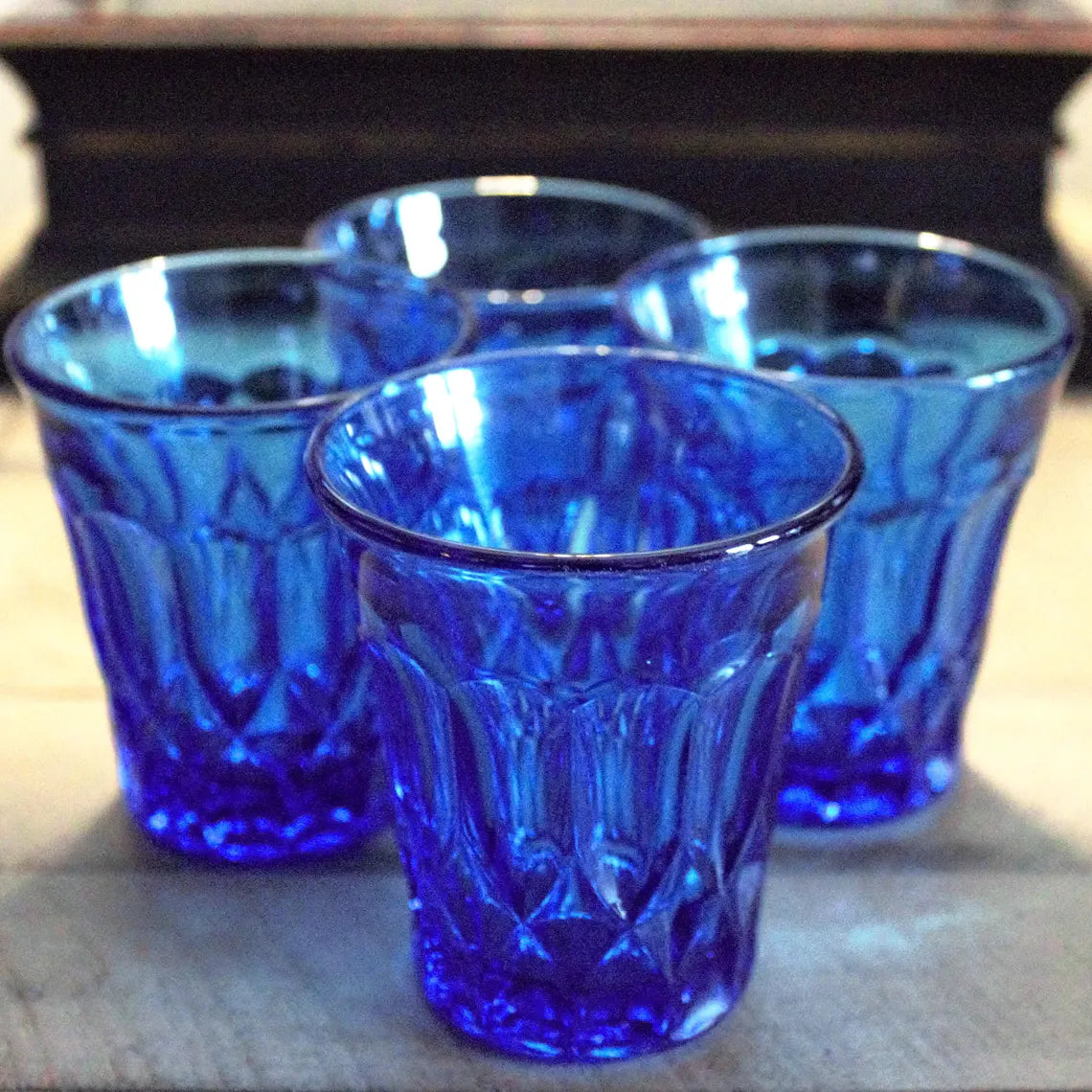 Three blue glass tumblers on a wooden surface