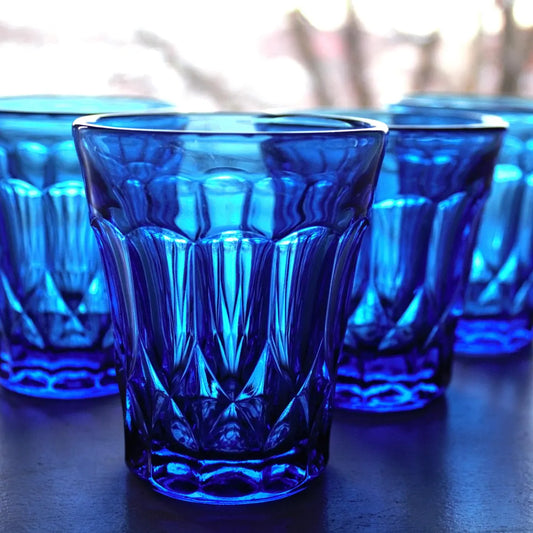 Set of blue glass tumblers with a textured design on a dark surface.