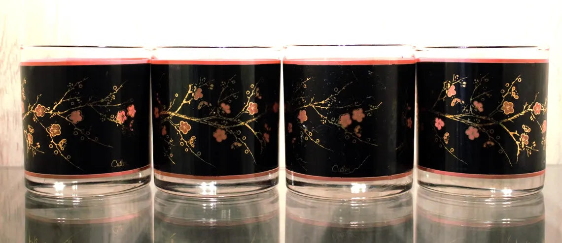 Four glass tumblers with floral designs on a black background
