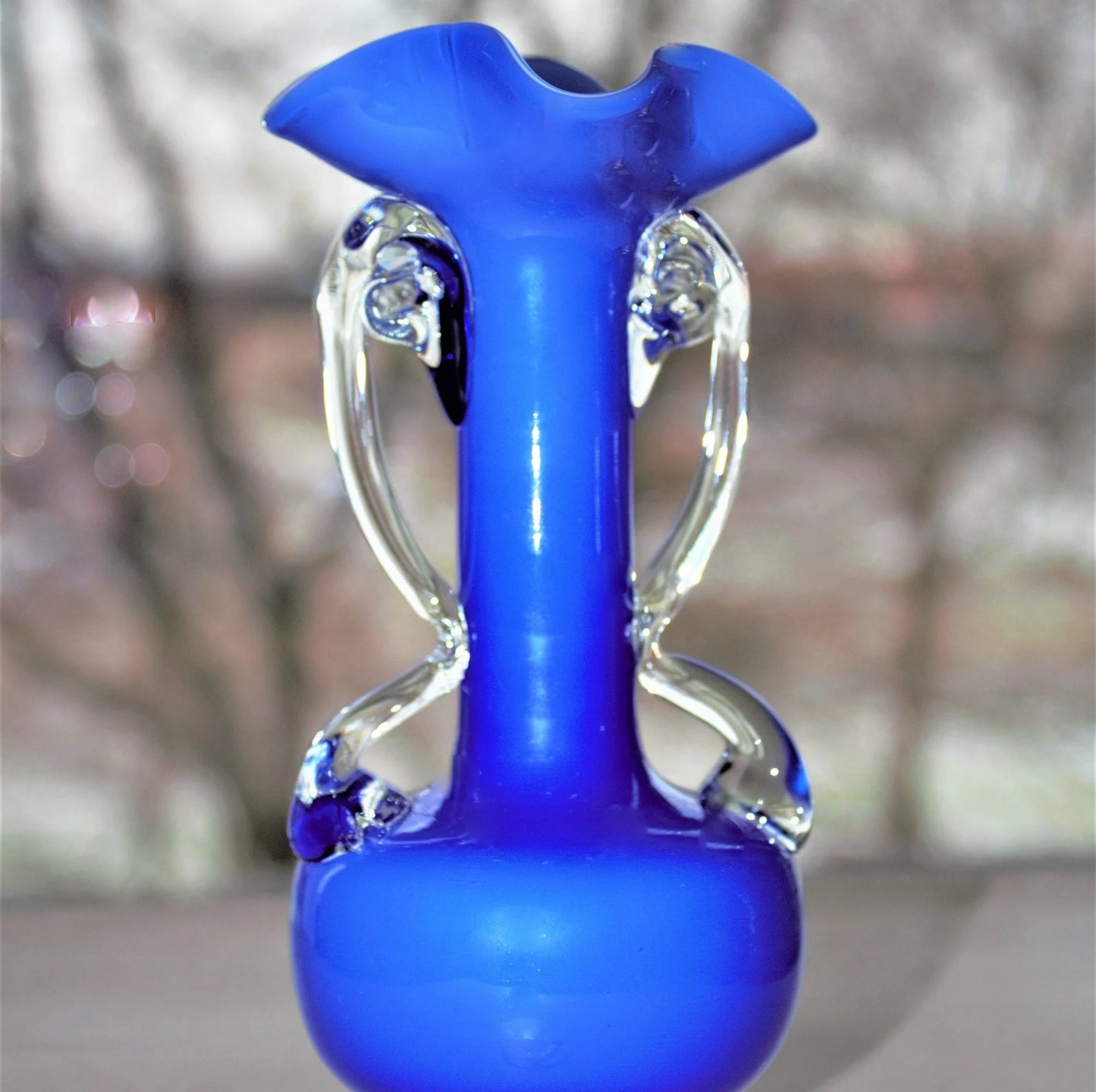 Blue glass vase with clear accents on a blurred background