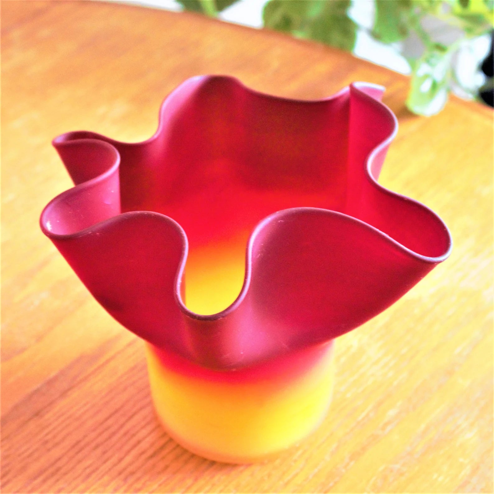 Colorful glass vase with wavy design on a wooden surface